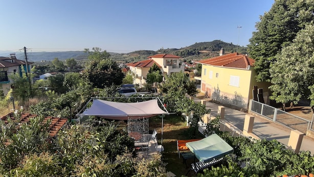 Ein Wohngebiet mit Häusern, einer Terrasse mit Gartenmöbeln und Blick auf die umliegende Landschaft.