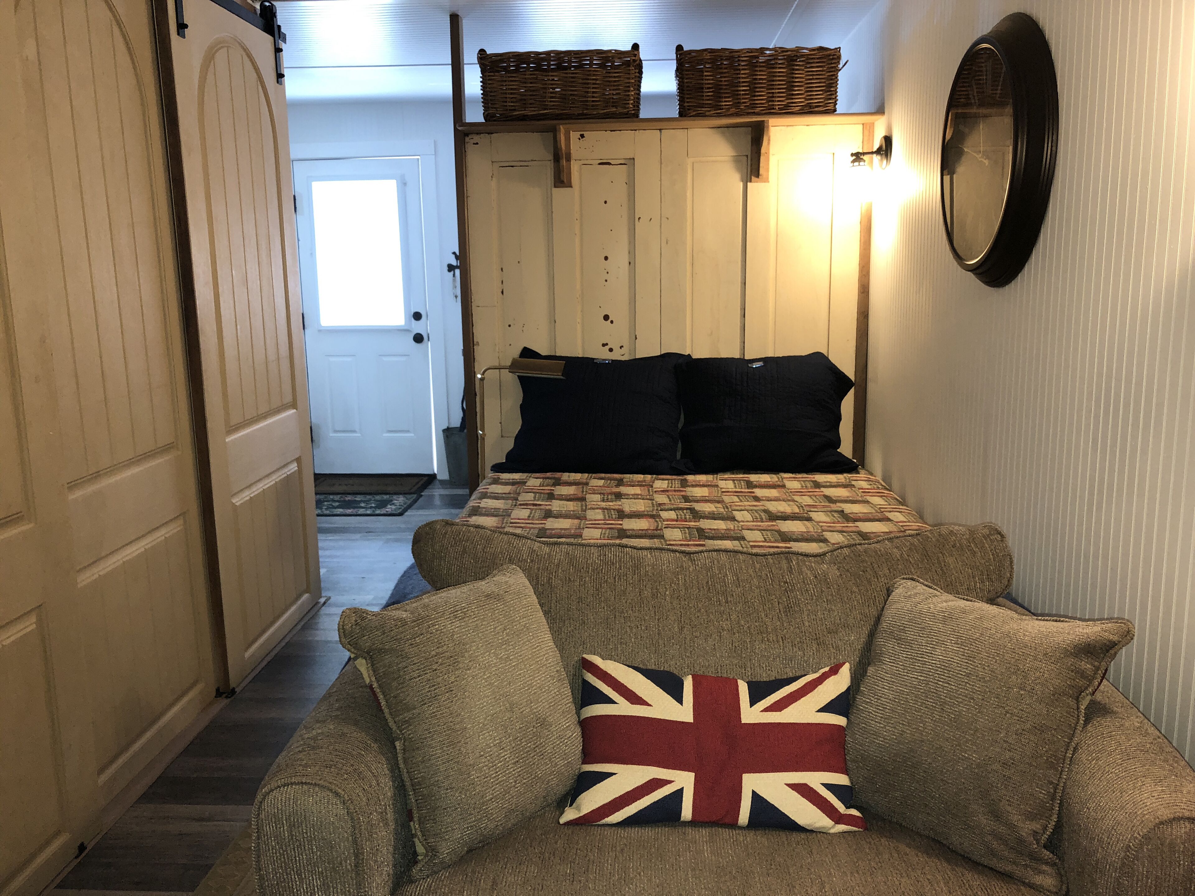 A cozy room with a bed, a sofa, and a door leading to another room.