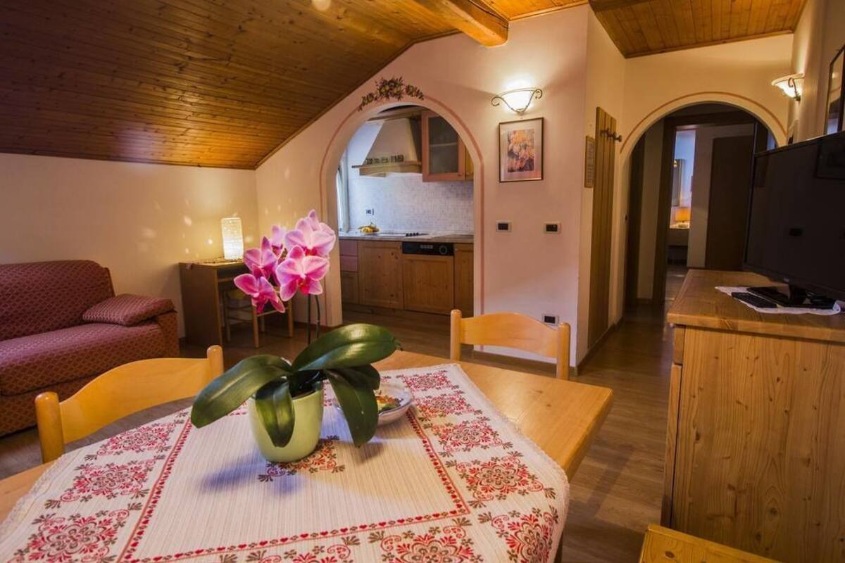 A cozy living room with a dining table, a sofa, and a kitchen in the background.