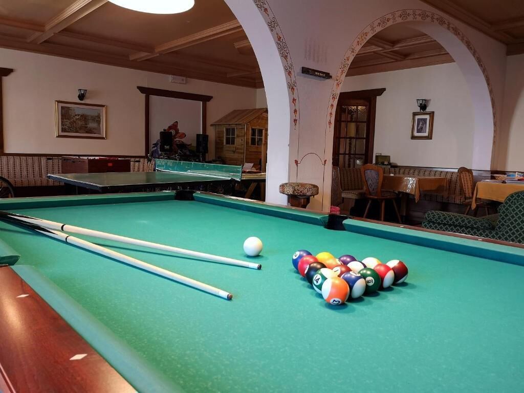 A pool table with balls and cues, a wooden bench, and a framed picture on the wall.