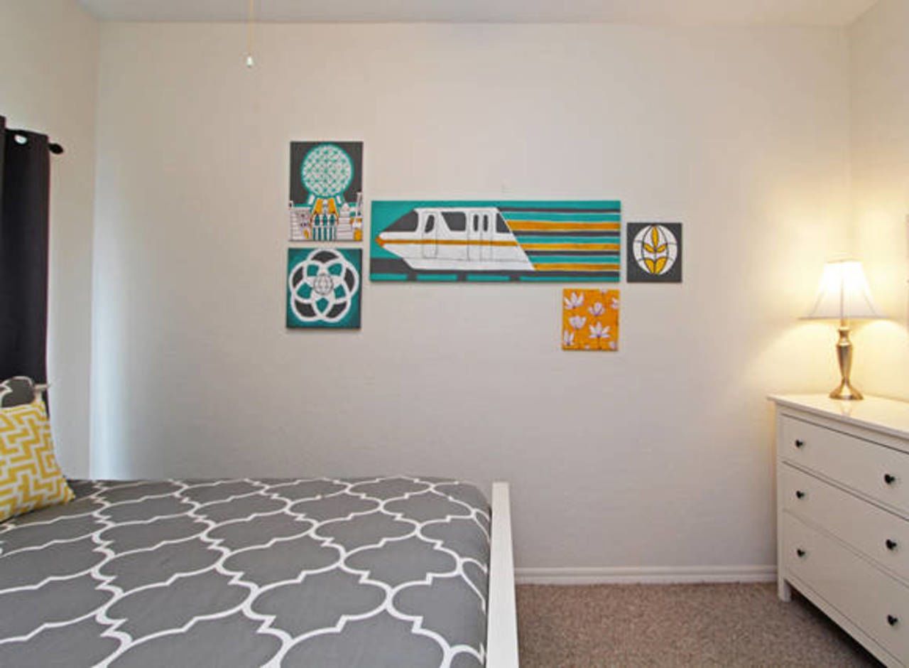 A bedroom with a bed, a dresser, and wall art.