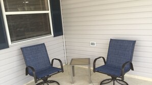 Two blue chairs with metal frames and wheels, a small table, and a window with blinds. - Patio Villa in Duval Village - Gas Golf Cart INCLUDED - 5 minutes to everywhere (The Villages)