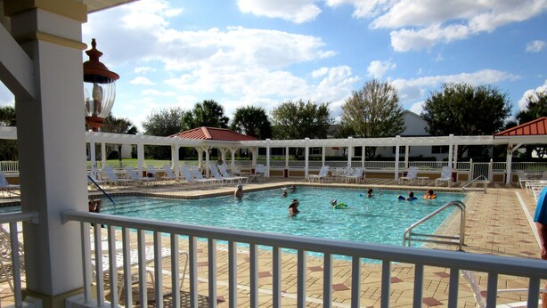 A pool area with multiple swimming pools, lounge chairs, and a covered seating area. - Patio Villa in Duval Village - Gas Golf Cart INCLUDED - 5 minutes to everywhere (The Villages)