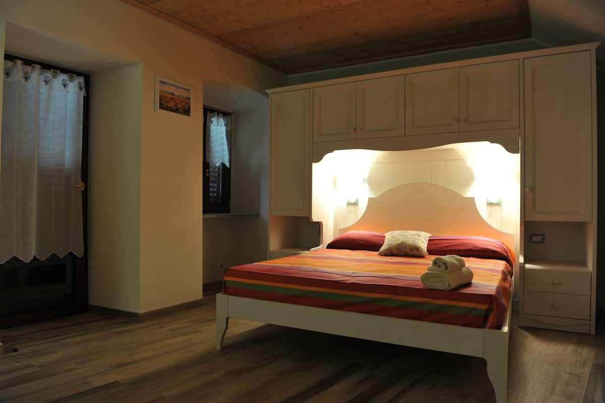 A bedroom with a bed, a nightstand, and a window with curtains.