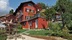 Ett rött hus i två våningar med en trädgård och en swimmingpool.