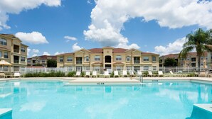 A swimming pool with lounge chairs and a white fence. - Magical Florida Getaway. (Davenport)