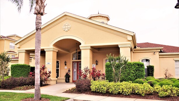 A two-story building with a beige facade, a central entrance with a red door, and a sign indicating the number 100. - Magical Florida Getaway. (Davenport)