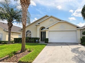 A single-story house with a garage, a front lawn, and a palm tree.