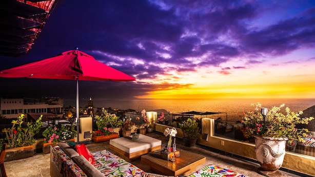 An outdoor seating area with a red umbrella, wicker furniture, and potted plants. - Private, Staffed Old Vallarta Casa with Rooftop Views, Art, Pool, & Walkability (Puerto Vallarta)
