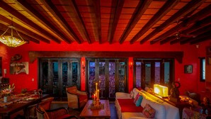 A cozy room with a wooden ceiling, a sofa, a dining table, and a view through large windows. - Private, Staffed Old Vallarta Casa with Rooftop Views, Art, Pool, & Walkability (Puerto Vallarta)