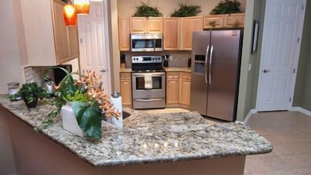 A kitchen with granite countertops, stainless steel appliances, wooden cabinets, and pendant lighting. - Kumar's Kastle (Davenport)