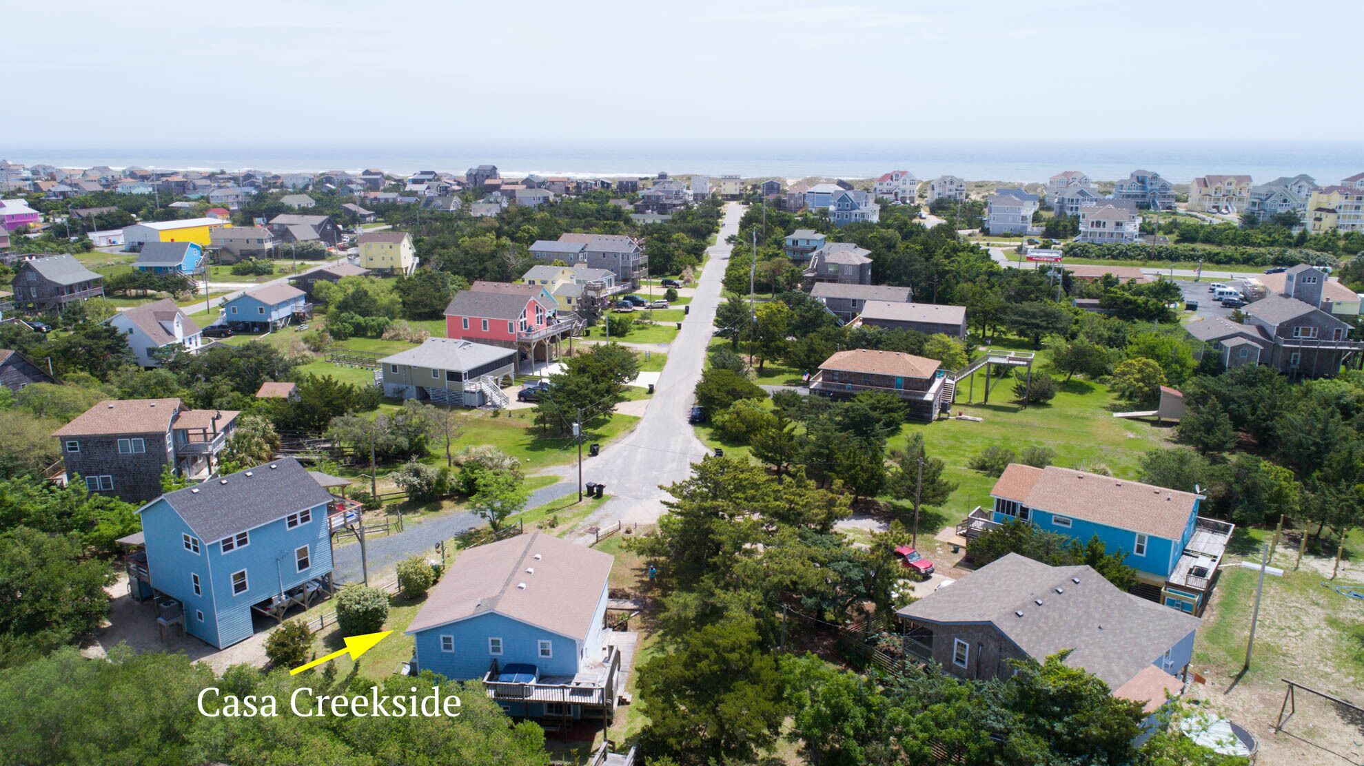 A residential area with houses, a central road, and a body of water in the background.