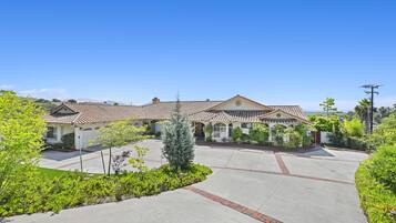 A two-story house with a tiled roof, a front driveway, and a landscaped garden.