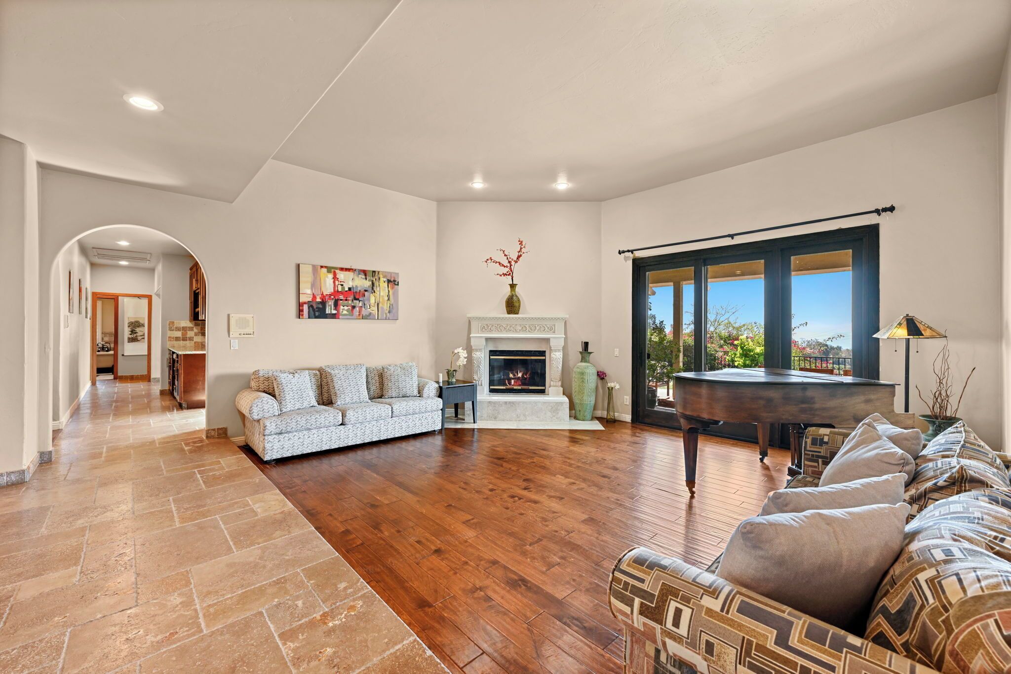 A spacious living room with hardwood flooring, a fireplace, a sofa, and a dining table.