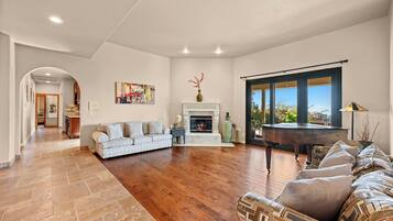 A spacious living room with hardwood flooring, a fireplace, a sofa, and a dining table.