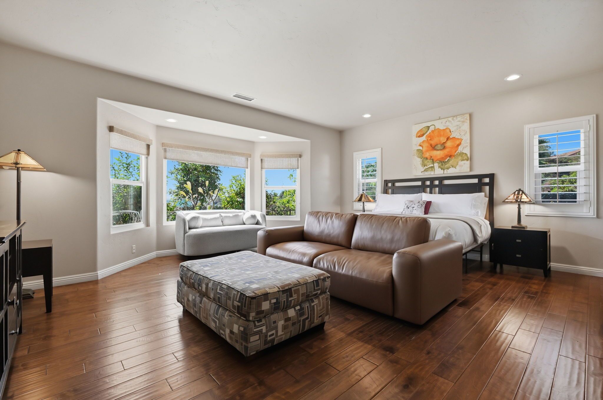 A bedroom with a bed, a sofa, a coffee table, and a nightstand.