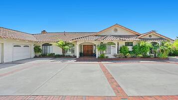 A two-story house with a tiled roof, a front entrance, and a driveway.