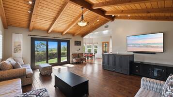 Amplia sala de estar con techo de madera, televisor grande y vistas al exterior.
