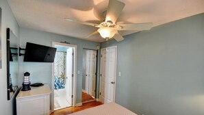 A bedroom with a bed, a ceiling fan, a TV mounted on the wall, and a door leading to another room. - 202 28th Ave Unit 6 1 Bedroom Condo (North Myrtle Beach)