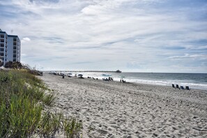 A beach with a pier extending into the ocean, sandy beach, and a building on the left. - 202 28th Ave Unit 6 1 Bedroom Condo (North Myrtle Beach)