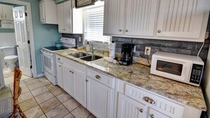A kitchen with white cabinets, granite countertops, a microwave, and a coffee maker. - 202 28th Ave Unit 6 1 Bedroom Condo (North Myrtle Beach)