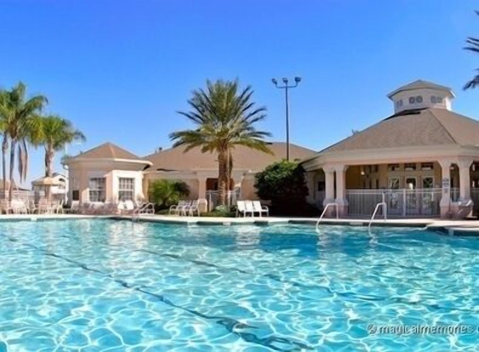 Une piscine à l’eau d’un bleu cristallin, entourée de palmiers et de chaises longues.