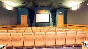 A theater with rows of seats, a large screen, and a projector at the front. - Silver Palm Retreat (Kissimmee)
