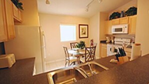 A modern kitchen with a central island, built-in appliances, and a dining area with chairs and a table. - Fun Florida Villa (Davenport)