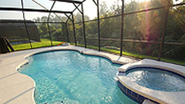 An outdoor swimming pool with a hot tub, surrounded by a fence and a grassy area. - Fun Florida Villa (Davenport)