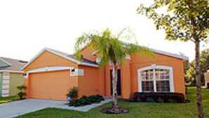 A residential house with a garage, a lawn, and a small tree. - Fun Florida Villa (Davenport)