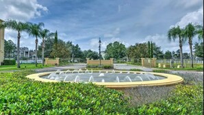 A landscaped area with a circular water feature, palm trees, and a fence. - Ridge Castle (Davenport)