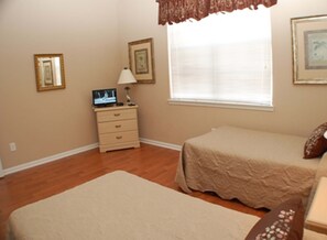 A bedroom with a bed, a dresser, a nightstand, and a window with blinds. - Ridge Castle (Davenport)