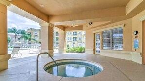A pool area with a hot tub, lounge chairs, and a view of surrounding buildings. - Ridge Castle (Davenport)