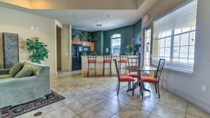 A spacious living area with a sofa, dining table, chairs, and a kitchen in the background. - Ridge Castle (Davenport)