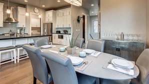 A modern kitchen with white cabinets, stainless steel appliances, and a dining area with a round table set for four.