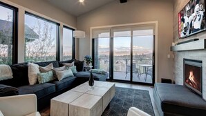 A modern living room with a large sofa, a coffee table, and a fireplace.