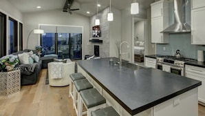 A modern kitchen with a large island, stainless steel appliances, and a bar area with stools.