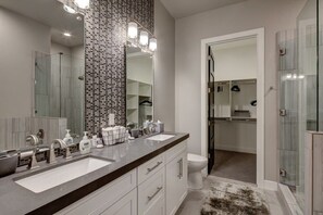 Un baño moderno con dos lavamanos, un espejo grande y una ducha a ras de suelo.