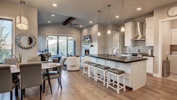A modern kitchen with a central island, pendant lights, and a dining area with a view.