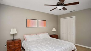 Ein Schlafzimmer mit einem Bett, zwei Nachttischen, einem Deckenventilator und einer Tür.