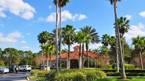 A hotel with a red-tiled roof, surrounded by palm trees and greenery. - Jewel in the Crown (Kissimmee)