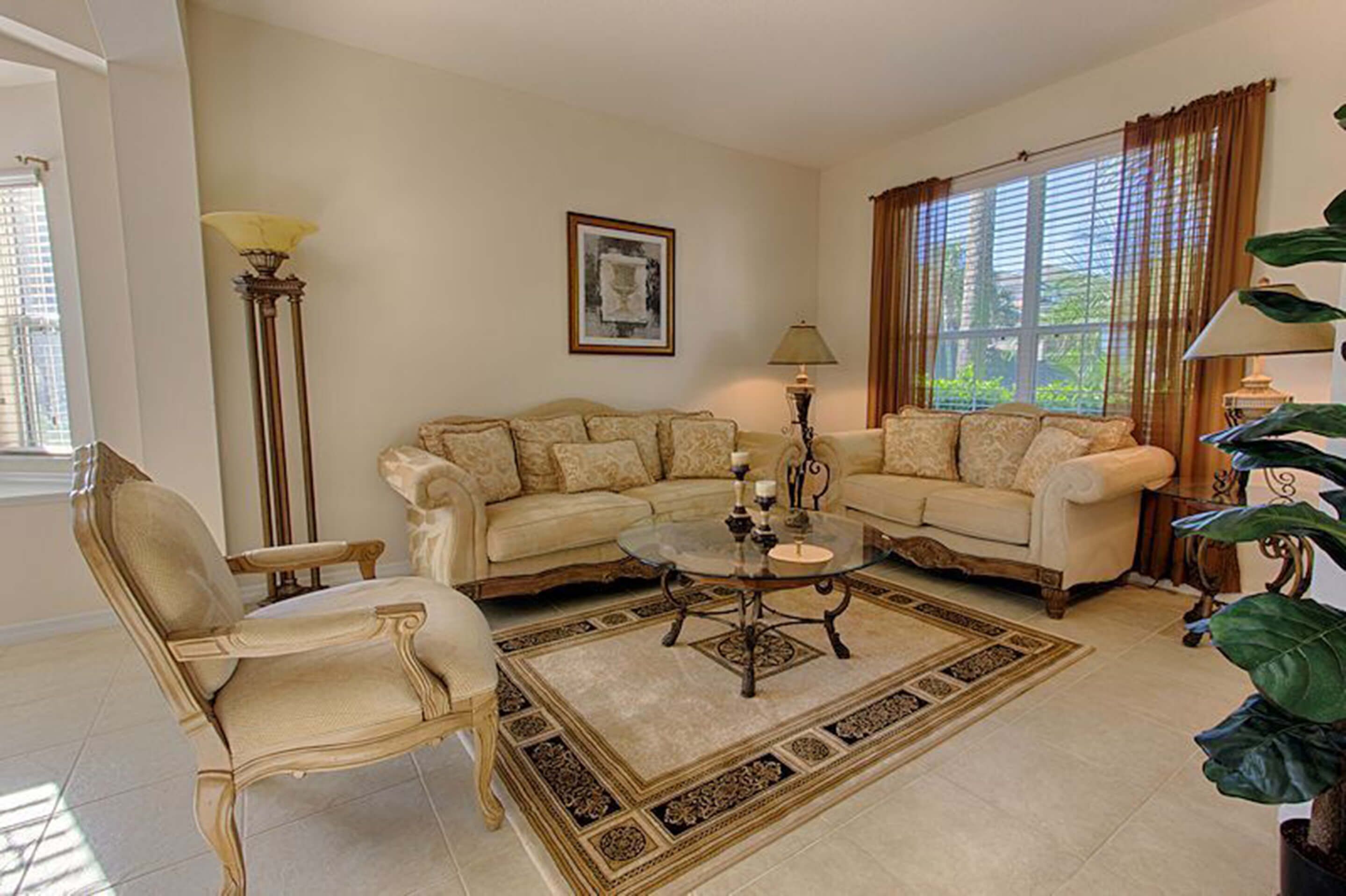 A living room with two sofas, a coffee table, a floor lamp, and a large window with curtains.