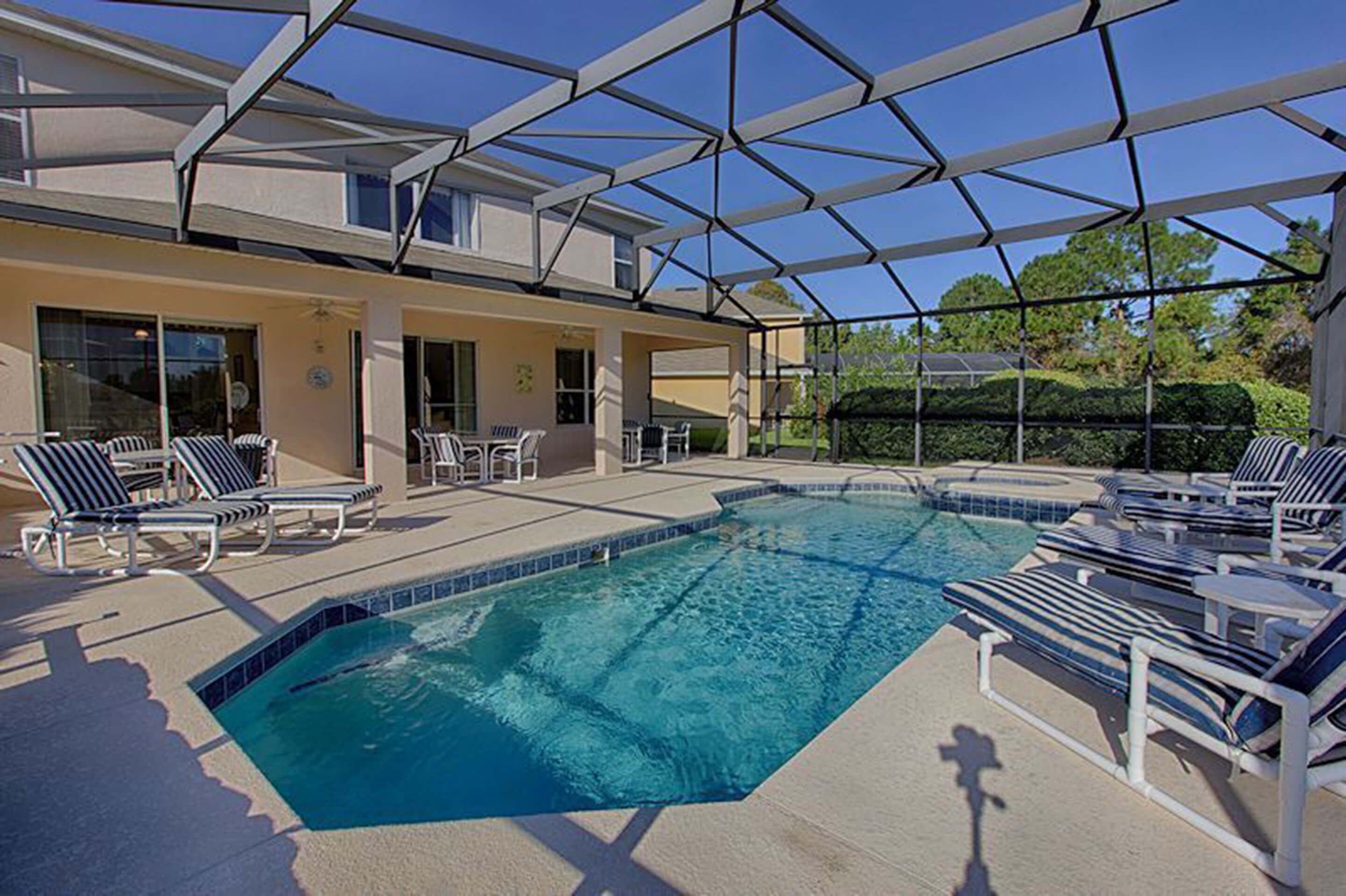 A swimming pool with lounge chairs and a covered patio area.