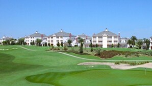 A golf course with bunkers and a clubhouse in the background. - Heritage Haven (Kissimmee)