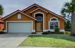 A two-story house with a garage, a central entrance, and a small front yard with a palm tree. - Awesome Villa (Davenport)