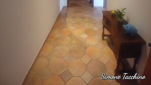 Un pasillo con suelo de patrón hexagonal, muebles de madera y cuadros en las paredes.