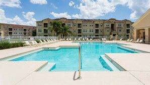 A swimming pool with lounge chairs and a building in the background. - Enchanted Retreat (Davenport)
