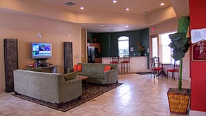 A spacious living room with a large sofa, a television, and a dining area in the background. - Enchanted Retreat (Davenport)