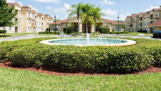A residential building complex with a central fountain, surrounded by manicured hedges and a well-maintained lawn. - Enchanted Retreat (Davenport)