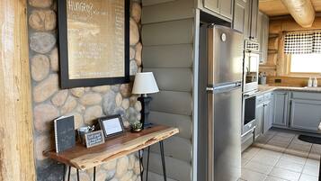 A kitchen with a stone wall, a framed menu, a laptop, and a refrigerator.